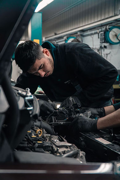 Monteur met handschoenen werkt aan het motorblok in een autogarage.
